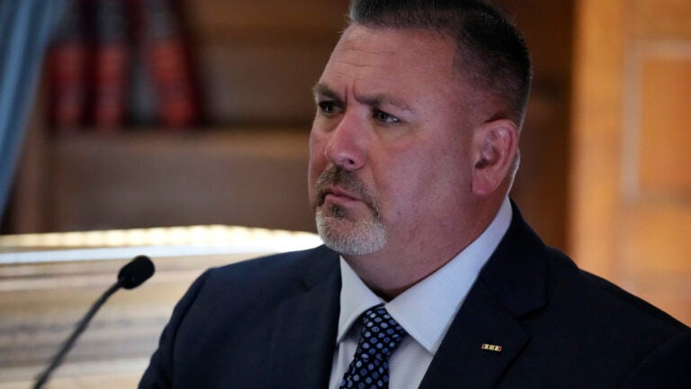 A witness in a suit seated at the witness stand.