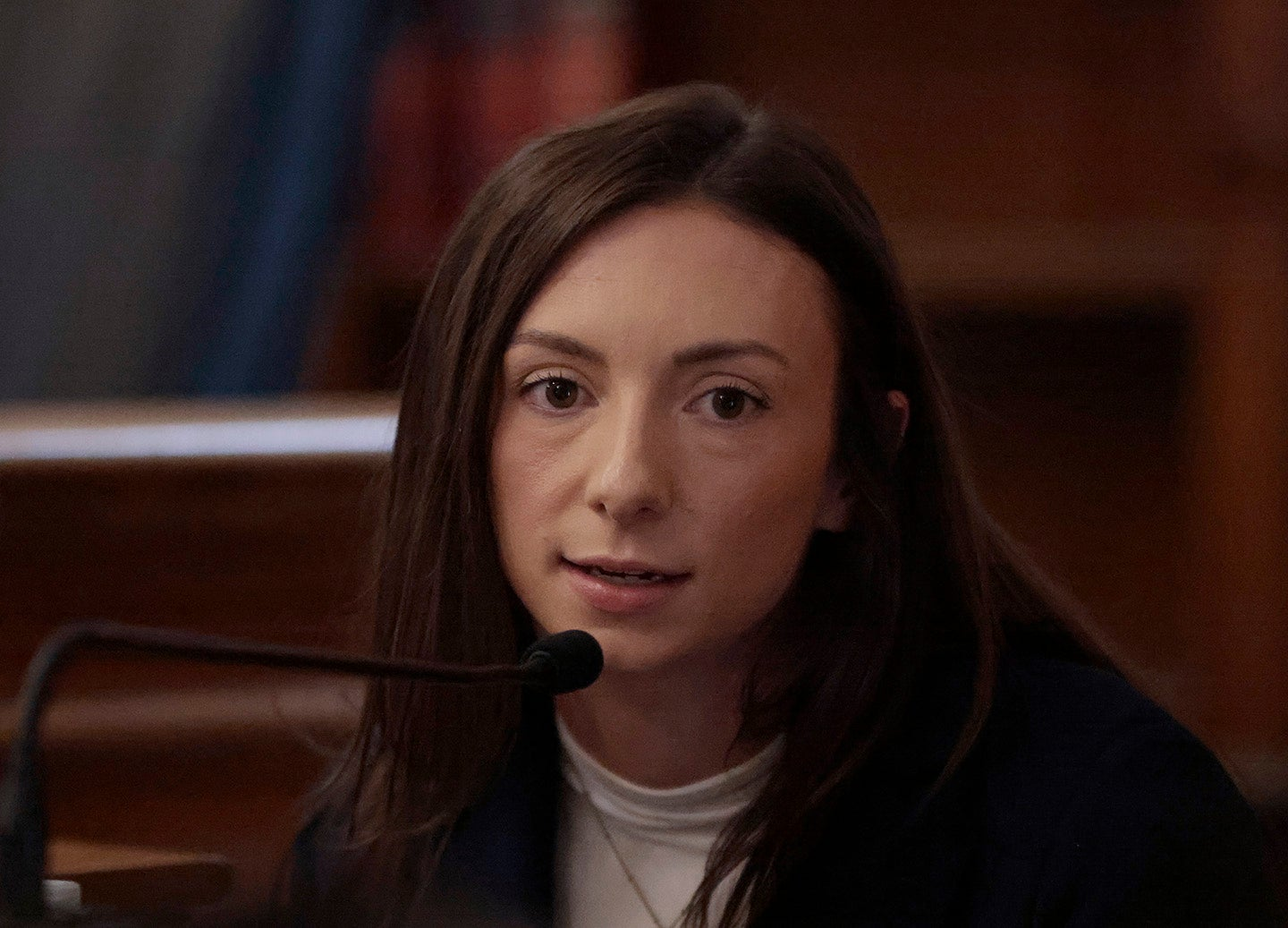 A witness at a courtroom microphone.