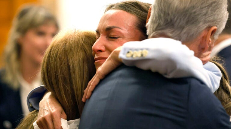 Three people embracing in a courtroom.