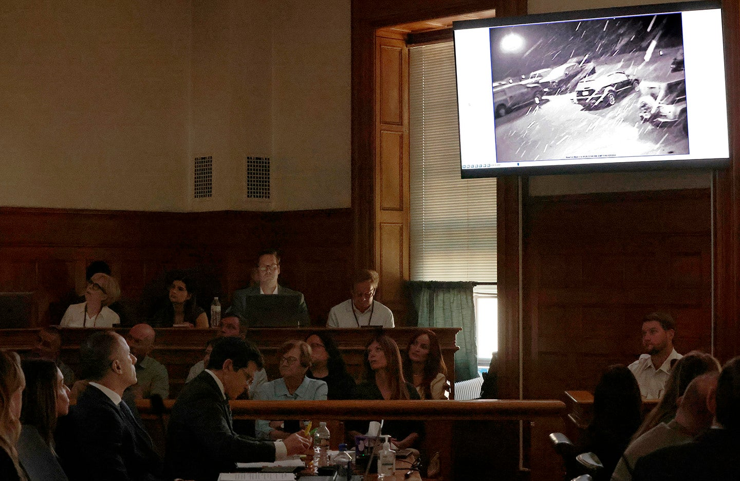 A courtroom monitor displaying a snowy parking lot with vehicles.